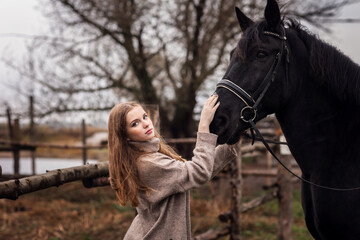 Obraz premium pretty young girl with long hair with a horse on an autumn day 