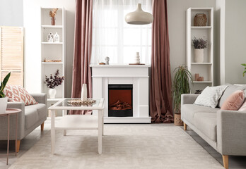 Interior of living room with modern fireplace, different home decorations and sofas