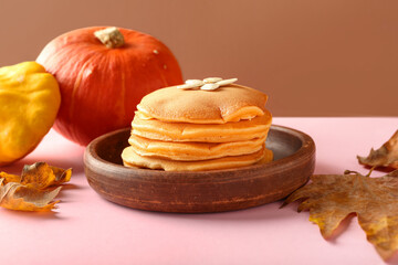 Plate with tasty pumpkin pancakes and seeds on colorful background