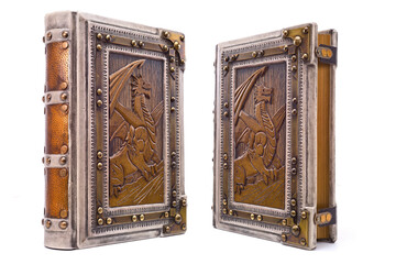 White leather book with the dragon symbol in wooden part of the cover, framed with a brass frame and corners 