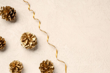 Golden pine cones and ribbon on beige grunge background