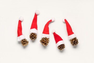 Christmas composition with pine comes and red Santa Claus hats on white background