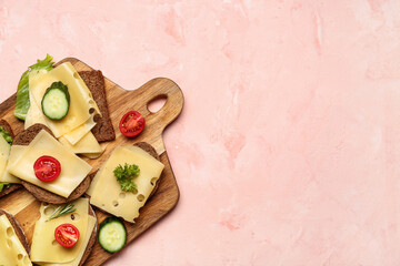 Tasty sandwiches with cheese, cucumber and tomatoes in board on pink background