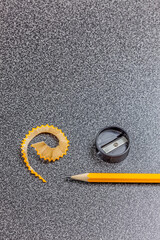 Pencil, pencil sharpener and pencil shaving on desk, close-up