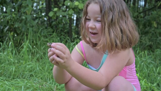 funny cute girl child playing on the beach with a frog in summer. High quality 4k footage