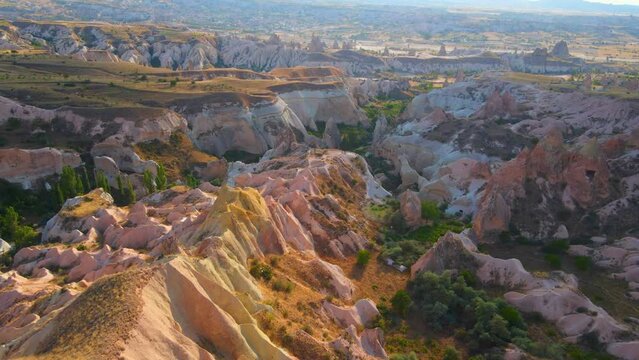 Experience the enchanting hues of the Red or Pink Valley near Goreme, Cappadocia, in this captivating aerial stock photo. The landscape, painted in warm tones, showcases the unique geological