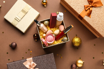 Christmas composition with different makeup products in gift box on brown background