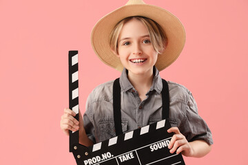 Little actor with movie clapper on pink background