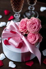 Beautiful surprise greeting for saint Valentine's or Women's Day, birthday or Anniversary for beloved. Fresh pink roses, gift box with sweets. Dark background. Holiday atmosphere