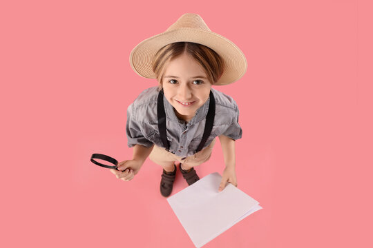 Little actor with magnifier and film script on pink background