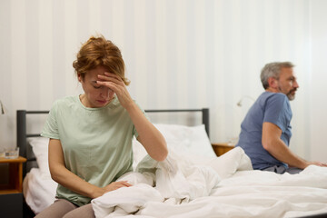 Obraz premium Couple sitting on different sides of bed not talking after argument