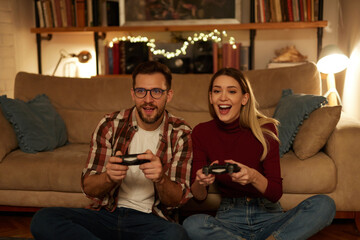 Obraz premium Young couple having fun at home playing video games