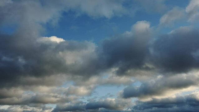 A cloud only time lapse of white, blue and gray clouds in a blue sky. The clouds are moving away from the viewer.
