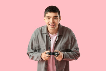 Fototapeta premium Happy young man with game pad on pink background