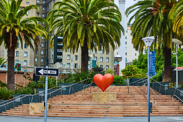 Red and yellow pride heart art on staircase with three palm trees in touristy Union Square in San...