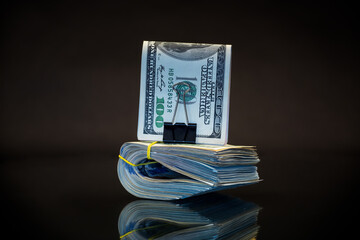 stack of dollar bills collected in an elastic band and a stationery clip