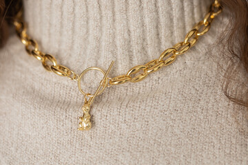 Close-up female in modern gold metal necklace chain with gold bunny pendant