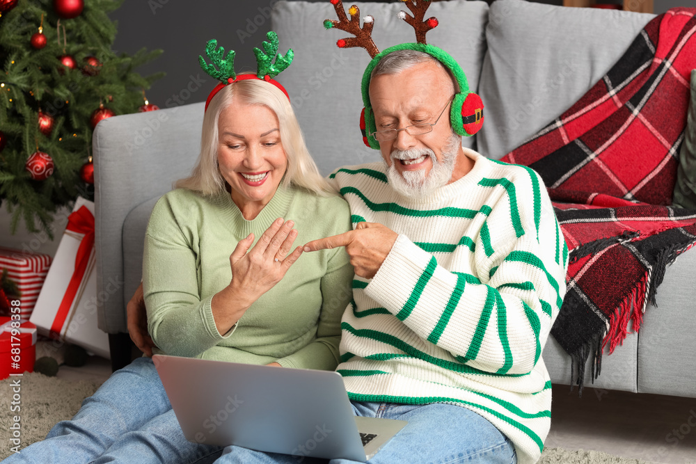 Canvas Prints Engaged mature couple with laptop video chatting at home on Christmas eve