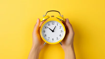 Foto op Aluminium hand holding yellow alarm clock on yellow background © Daniel