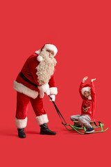 Santa Claus and cute little boy sledding on red background