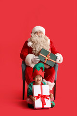 Santa Claus and cute little elf with Christmas gifts on red background