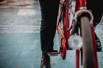 A woman stands next to a vintage red bicycle close-up. Blurred background