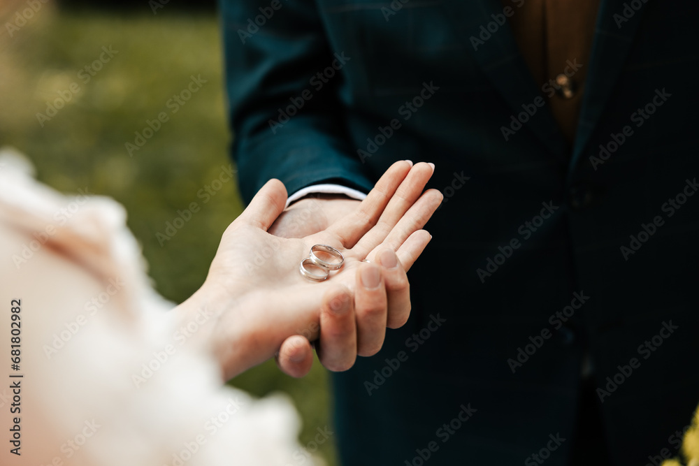 Wall mural the bride and groom hold wedding rings in their hands