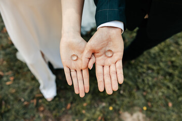 the bride and groom hold wedding rings in their hands