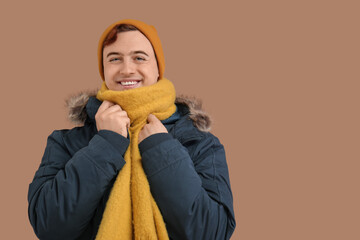 Young man in winter clothes on brown background