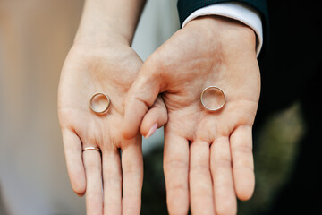 the bride and groom hold wedding rings in their hands