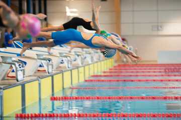 Swimmer girls start from the starting table in the pool - 681806380