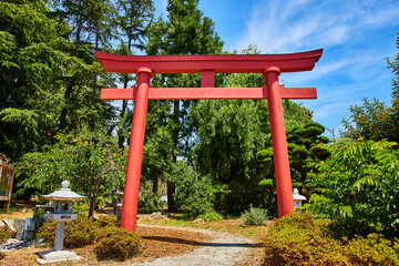 Fototapeta na wymiar Red Torii Gate in Japanese Garden with stone lanterns lining path at The Gardens at Lake Merritt