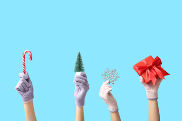 Female hands in warm gloves with Christmas decorations and gift box on color background