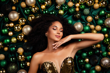 Portrait of adorable beautiful sensual lady laying on xmas tree baubles luxury background emerald...