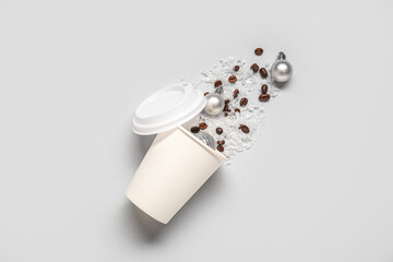 Cup with coffee beans, snow and Christmas balls on light background