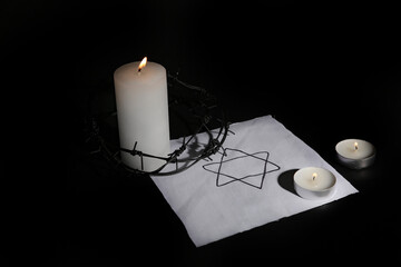 Burning candles with barbed wire and David star on dark background. International Holocaust...