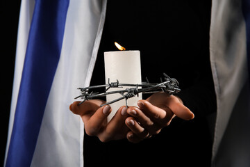 Jewish woman with flag of Israel, burning candle and barbed wire on dark background, closeup....