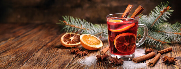 Mulled wine in glass mug with spices. Christmas hot drink on wooden table background. Close-up side...
