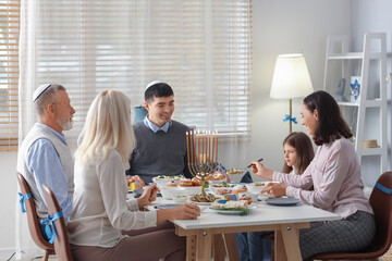 Little girl having dinner with her family at home on Hanukkah