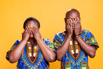 African american couple covering eyes with arms, showing hear no evil three wise monkeys portrait....