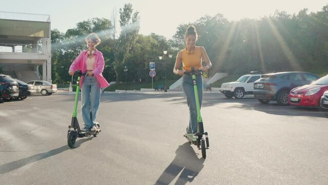 Two friends having fun riding shared electric push scooters in the city.