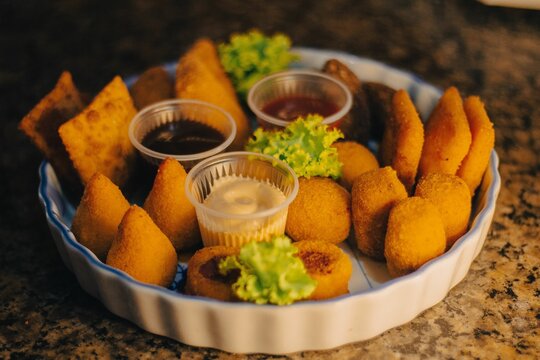 coxinha, cheese balls, mini chicken pot pies, kibbeh, risoles, pastries filled with meat or cheese, Lebanese meat pies, mini sandwiches, codfish fritters, and meat croquettes