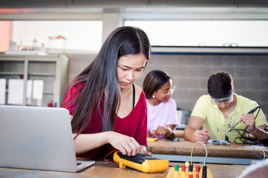 Portrait of a young Chinese student concentrating on her electricity meter at technical vocational school. Lesson in university internship. Concept of people education and technology.