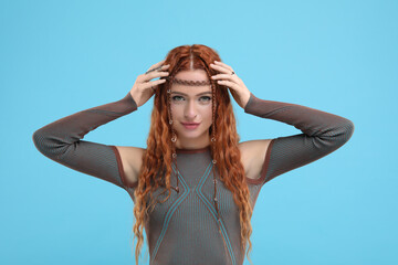Beautiful young hippie woman on light blue background