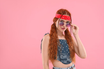 Stylish young hippie woman in sunglasses on pink background, space for text