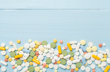 Different medical pills and capsules on wooden background, top view