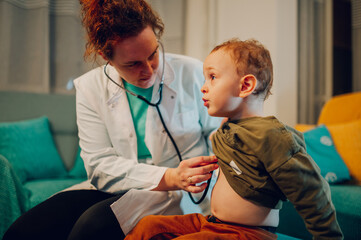A female doctor is using stethoscope to examine kid's lungs at home.