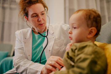 A doctor is sitting at home with a little patient during checkup.