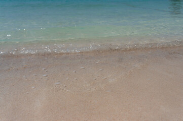 Fototapeta na wymiar Soft turquoise sea waves on the sandy beach.
