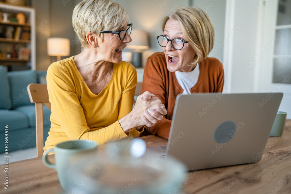 Wall mural Senior women two females hold credit card online shopping at home